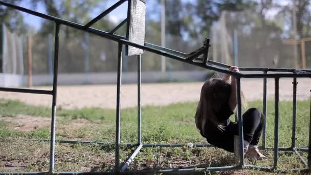 Niña con chaqueta negra y polainas jugando en la construcción deportiva en el parque — Vídeo de stock