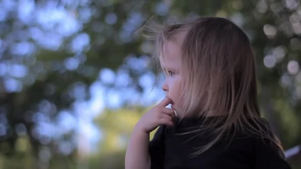 Portret van een weinig verward meisje kijkt rond in verlegenheid gebracht en Gnaws vinger — Stockvideo