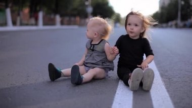 Gülüyor ve rüzgarlı bir yolda dışında oturan Tablet oynayan iki küçük güzel kız
