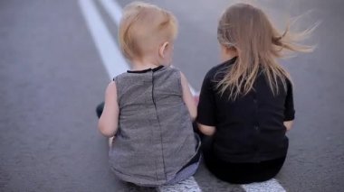 İki güzel neşeli kız kameraya sırt üstü rüzgarlı Road ve oyun ile bir kırık Tablet, sonra bir görünüyor etrafında kalkar ve yaprakları ile oturup