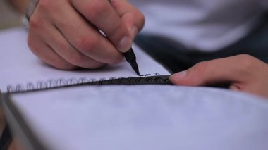 Elini bir çelik bileklik ve siyah kalemi yazılı bir not defteri olarak