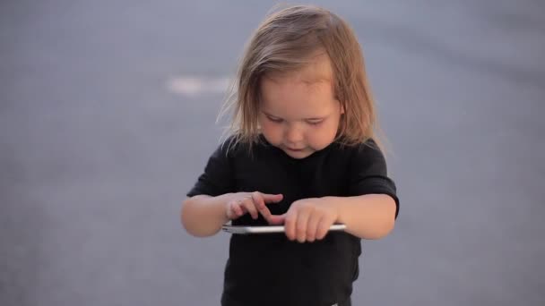 Zlomyslný holčička hraje s tabletem na ulici a pak běží rychle a kamera ji sleduje — Stock video