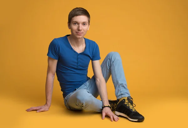 Genç adam yerde oturuyor.