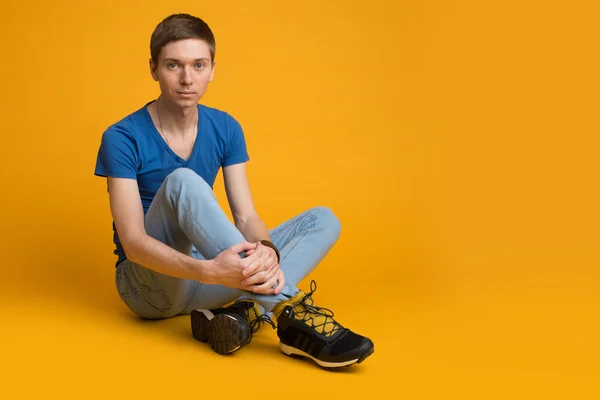 Genç adam yerde oturuyor.