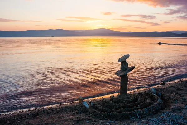 Montón de piedras en la playa al atardecer horizonte — Foto de Stock