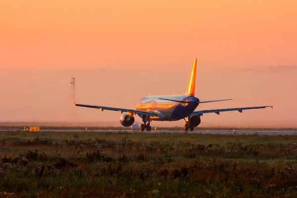 Самолет на взлетно-посадочной полосе ранним туманным утром — стоковое фото