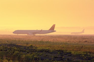 Planes on the taxiway in the early foggy morning clipart