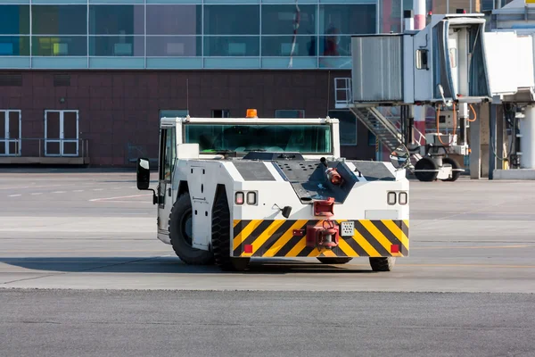 Tractor de remolque de avión cerca del puente de embarque de pasajeros — Foto de Stock