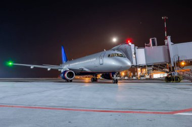 Gece havaalanı önlüğüyle Jet Köprüsü 'nde modern yolcu uçağı.