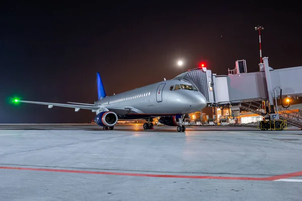 Gece havaalanı önlüğüyle Jet Köprüsü 'nde modern yolcu uçağı.