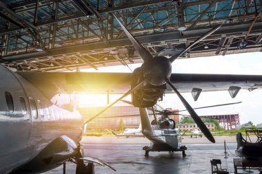 Yolcu turbo pervaneli uçak ve helikopter hangarda. Rotorcraft ve uçaklar bakım altında. Uçuş işlemleri için mekanik sistemler denetleniyor