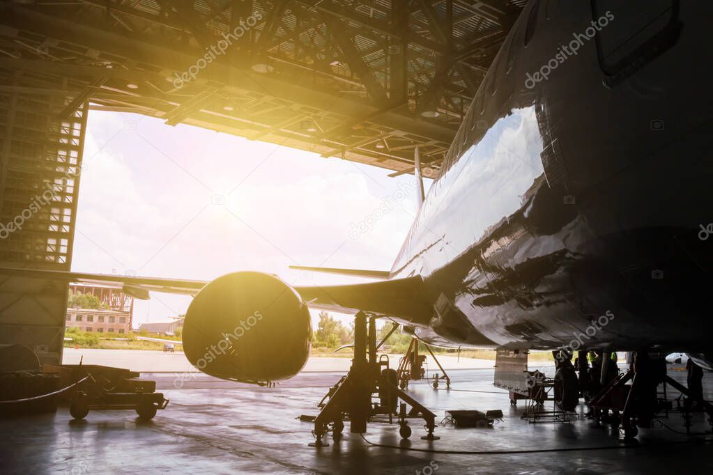 White passenger airliner under maintenance in the hangar. Repair of jet plane and checking mechanical systems for flight operations