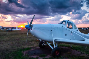 Hava sahasında havacılık kimyasalları taşıyan bir uçağı gün batımının manzarasına karşı yakın plan çekiyoruz.