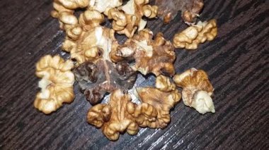 Masanın üzerindeki ceviz çekirdeğinin yakın plan görüntüsü, doğal kabuğundan kurtarılmış besin zengini eti ortaya çıkarıyor ve kendine özgü dokusunu, ılık altın tonlarını ve karmaşık kıvrımlarını gözler önüne seriyor..