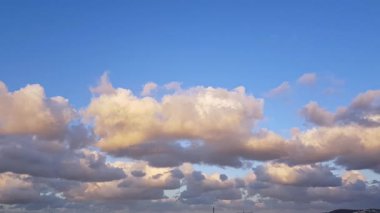 Çerçevenin üst yarısına dramatik bir gökyüzü hakim. Ufuk boyunca sürüklenen engebeli, dokulu bulutlar ve sahneyi nazikçe aydınlatan sıcak bir parıltı. Bulutun üstünde, gökyüzü açık kalır