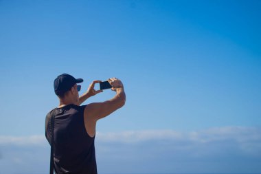 Akıllı telefonlu bir adam doğada selfie çekiyor.