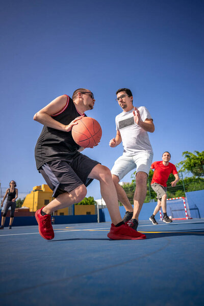 Friends, boys and girl having fun laughing and playing basketball.