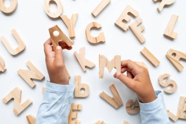 Beyaz arka planda tahta alfabe harfleri tutan çocuk elleri. Yüksek kalite.