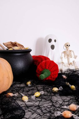 Halloween decor with ghost figurine, candy, and skeleton on black netting. High quality.