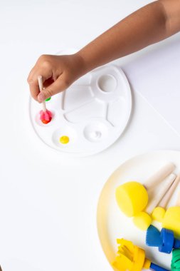 Beyaz palette ahşap fırçalar kullanarak renkli boyalarla çocuk resimleri. Yüksek kalite.