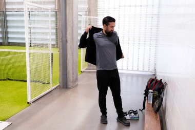 Genç beyaz erkek spor merkezinde kapalı alanda oynanacak futbol maçına hazırlanıyor. Yüksek kalite.