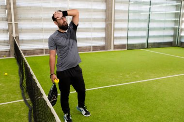 Beyaz, yetişkin bir erkek. Maçtan sonra tenis kortunda kürek çekiyor. Yüksek kalite.