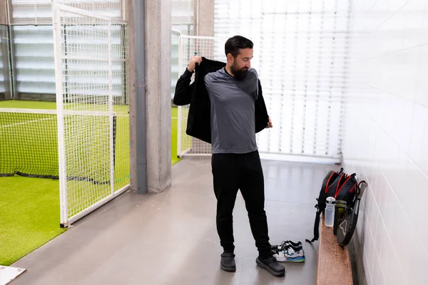 Genç beyaz erkek spor merkezinde kapalı alanda oynanacak futbol maçına hazırlanıyor. Yüksek kalite.