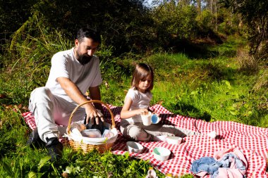 Baba ve kızı güneşli bir günde dışarıda pikniğin tadını çıkarıyorlar. Yüksek kalite.