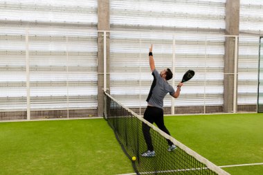 Genç beyaz erkek içeride raket tenisi oynuyor. Yüksek kalite.