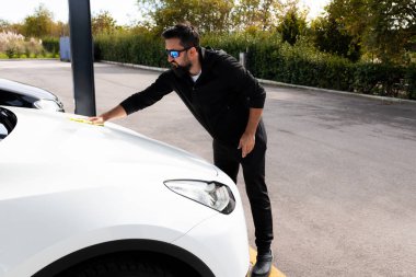 Beyaz erkek, araba yıkamada araba kaputunu temizliyor..