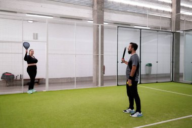 Genç yetişkinler kapalı mahkemede Padel oynuyorlar. Yüksek kalite.