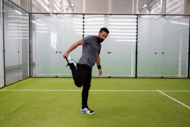 Beyaz erkek, kapalı alanda padel kortunda geriniyor. Yüksek kalite.