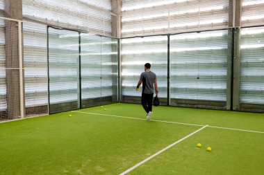 Erkek, kapalı sahada ekipmanla tenis oynuyor. Yüksek kalite.