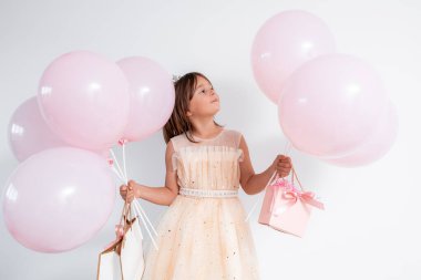 Pembe balonlu ve hediye çantalı beyaz bir kız çocuğu kutluyor. Yüksek kalite.