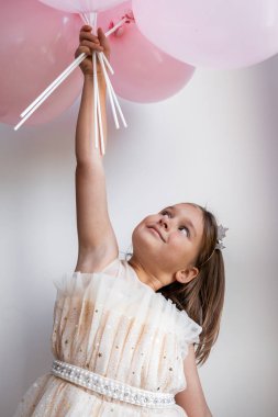 Beyaz elbiseli pembe balonlar tutan beyaz bir kız. Yüksek kalite.