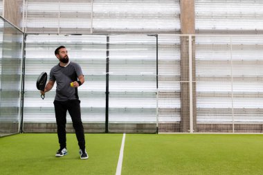 Genç İspanyol erkek kapalı sahada Padel tenis oynuyor. Yüksek kalite.