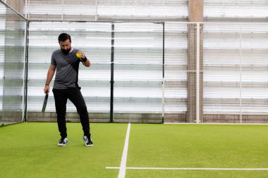 Beyaz erkek, kapalı sahada tenis oynamaya hazırlanıyor. Yüksek kalite.