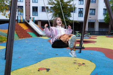 Kafkasyalı genç kız renkli şehir parkında neşeyle sallanıyor. Yüksek kalite.