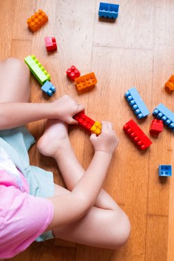 Çocuk ahşap zeminde renkli yapı taşlarıyla oynuyor. Yüksek kalite.