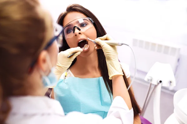 Overzicht van de preventie van cariës. Vrouw bij de tandarts stoel tijdens een tandheelkundige ingreep. — Stockfoto