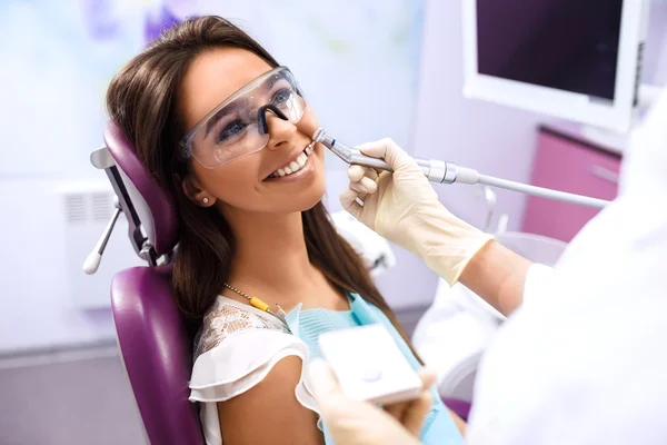 Översikt av tand karies förebyggande. Kvinnan vid tandläkarens stol under en tandingrepp. Vacker kvinna leende — Stockfoto