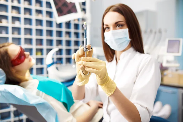 Jeringa. una inyección. cauterizado. Retrato de dentista femenina en el consultorio. Concepto de cuidado dental . — Foto de Stock