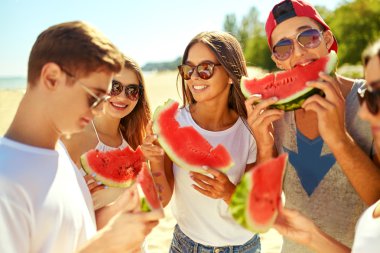 Gençler kumsalda karpuz yeme. İnsanlar yaz saati tadını çıkarın. Plajda eğlence. Büyük yaz ruh. güneşli gün