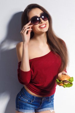 Young beautiful girl with a burger in her hands. Studio shot. Model. Fast food meal