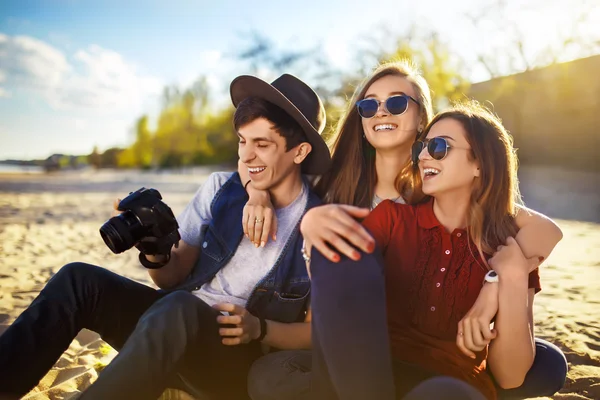 En grupp vänner umgås på stranden. De skrattar och ler. Vänlig atmosfär — Stockfoto