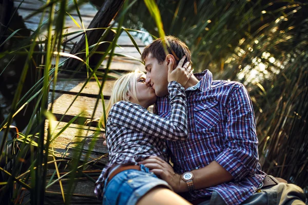 Um jovem casal beijo no parque ao nascer do sol — Fotografia de Stock