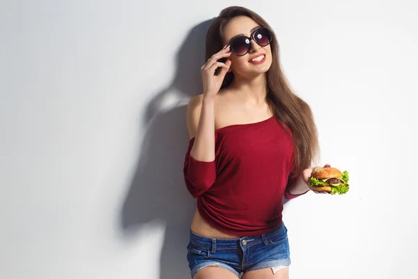 เด็กสาวสวยที่มีเบอร์เกอร์อยู่ในมือของเธอ สตูดิโอถ่าย แบบจําลอง อาหารจานด่วน — ภาพถ่ายสต็อก