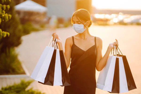 Gyönyörű Védő Orvosi Maszkban Bevásárlószatyrokkal Pláza Közelében Sétálva Naplementekor Bevásárlás — Stock Fotó