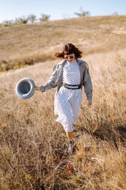 Sonbahar tarlasında yürüyen şık bir kadın. Rahatlama, keyif alma, doğayla baş başa kalma..