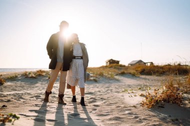 Deniz kenarında yürüyen ve kucaklaşan genç bir çift. Birlikte eğleniyoruz. Moda, yaşam tarzı ve sonbahar havası.